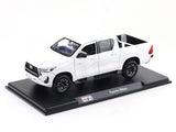 Model of a white Toyota Hilux on a black display stand with a white background